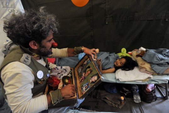 An Israeli medical clown entertains a Nepalese earthquake victim during a visit to a makeshift army camp in Kathmandu on May 6, 2015. The 7.8 magnitude earthquake which struck the Himalayan nation on April 25, 2015, has had a devastating impact on the economy of Nepal where tourism attracted almost 800,000 foreign visitors in 2013 -- many of them climbers heading straight to Mount Everest but also less adventurous tourists seeking the rich cultural history of Kathmandu. AFP PHOTO / PRAKASH MATHEMA