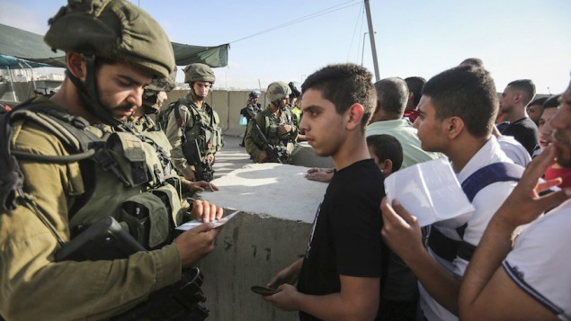 Des soldats israéliens contrôlent les cartes d'identité de Palestiniens au checkpoint de Qalandia entre la ville de Ramallah, en Cisjordanie, et Jérusalem, le 1er juillet 2016. (Crédit : Flash90)