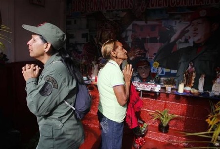 Deux femmes prient à l’occasion du premier anniversaire de la mort de l’ancien président à l’autel « Saint Hugo Chavez » dans un quartier de Caracas le 4 mars 2014. 