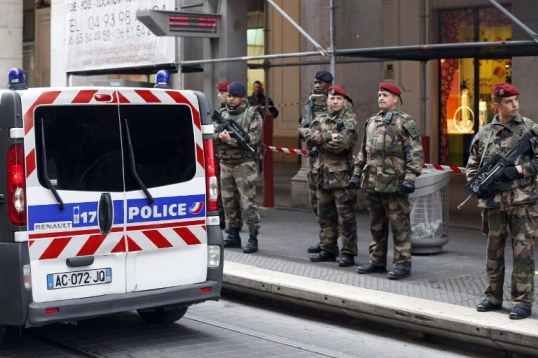 Soldiers stand guard next to a Police van outside the Jewish Community Center where three soldiers, patrolling outside the center as part of the country's Vigipirate security measures, were attacked by a man with a bladed weapon, on February 3, 2015 in downtown Nice, southeastern France. The soldiers were taken over by the emergency services, one was wounded in the arm and another in the face, and their vital prognosis is not engaged. Police sources said the author of the attack was arrested. AFP PHOTO / VALERY HACHE