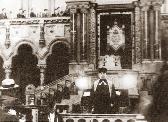 Joseph Borin devant l'Arche sainte de la synagogue du quai Kléber vers 1935.On aperçoit au 1er étage une partie des membres de la chorale dirigée par Bernard Bochner. Coll. Elie Meyer ; cette photo est extraite de l'ouvrage de Jean Daltroff, La Synagogue du quai Kléber.