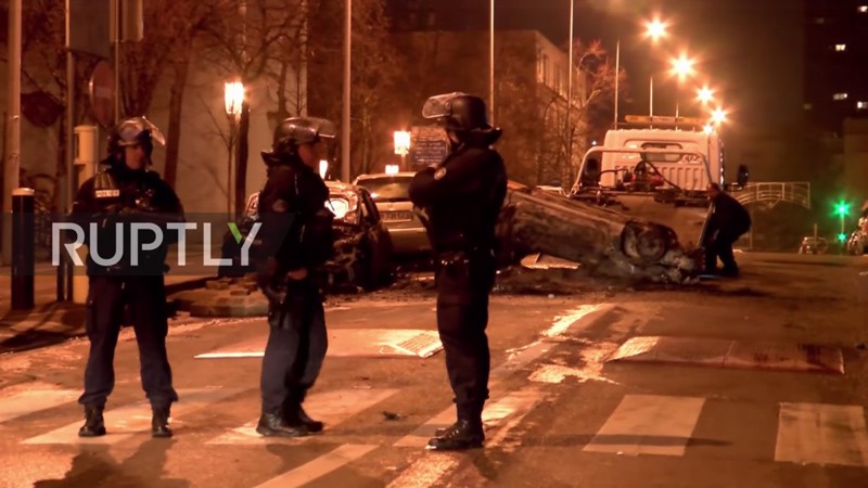 Des policiers sont en observation tandis qu'une voiture, qui a été détruite par les émeutiers dans une banlieue de Paris, est enlevée, le 13 février 2017. (Source de l'image: capture d'écran d'une vidéo Ruptly)